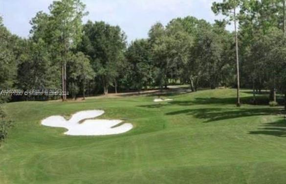 Expansive grounds featuring a manicured fairway, sand bunkers, and mature perimeter trees