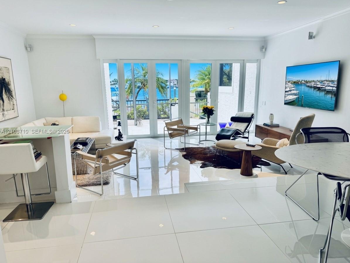 Open-concept living space featuring high-gloss tile flooring, recessed lighting, and multi-panel glass doors with a water-facing exterior