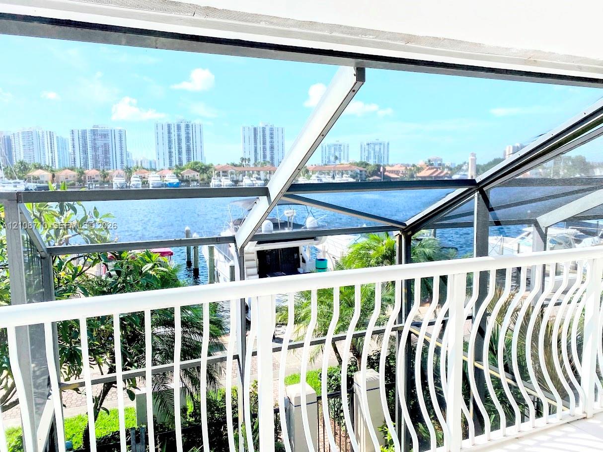 Screen-enclosed balcony featuring white metal railings, water frontage, and integrated structural framing
