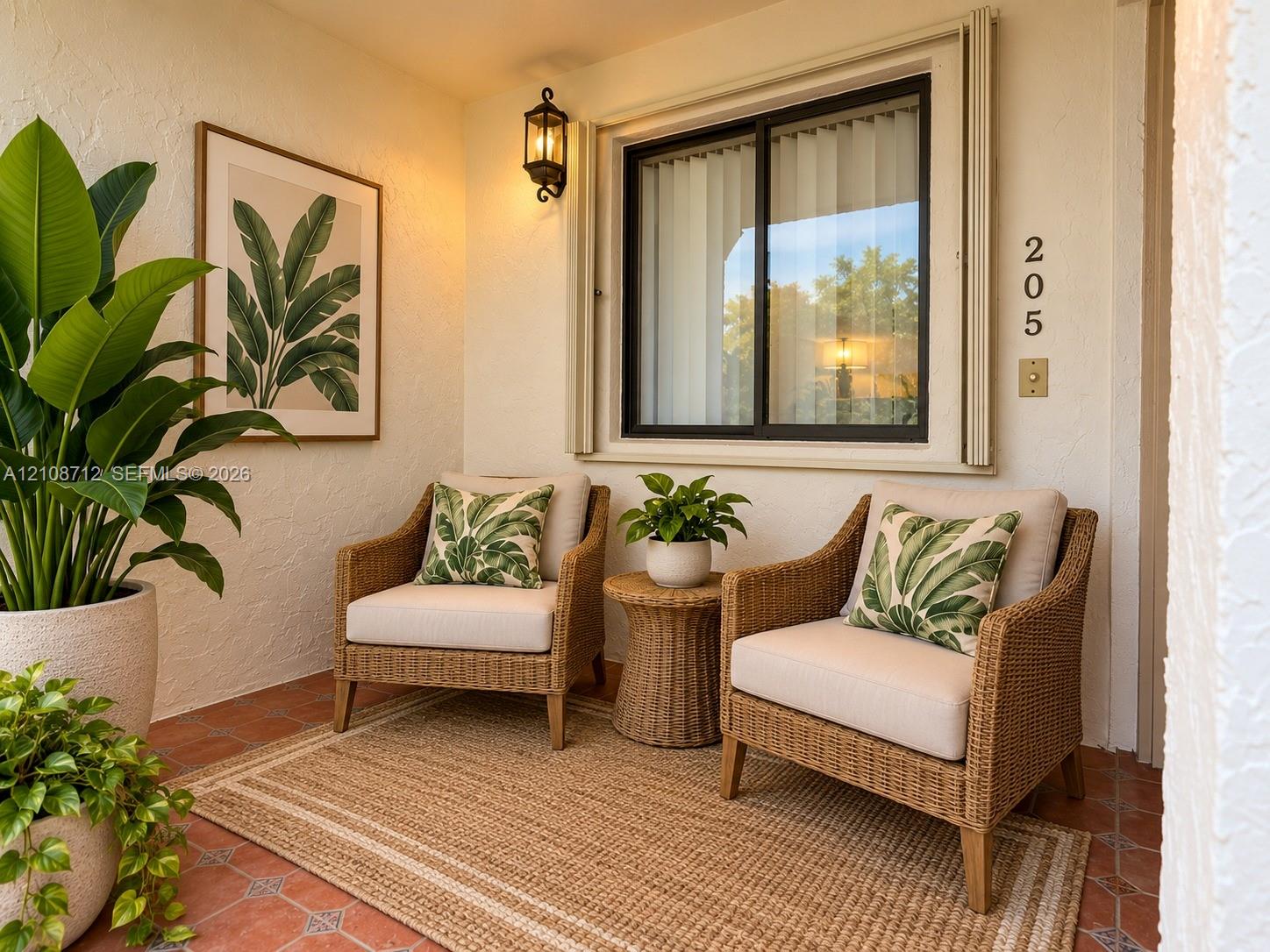 Stage Covered entryway featuring terracotta tile flooring, exterior wall-mounted lantern-style lighting, and a sliding glass window