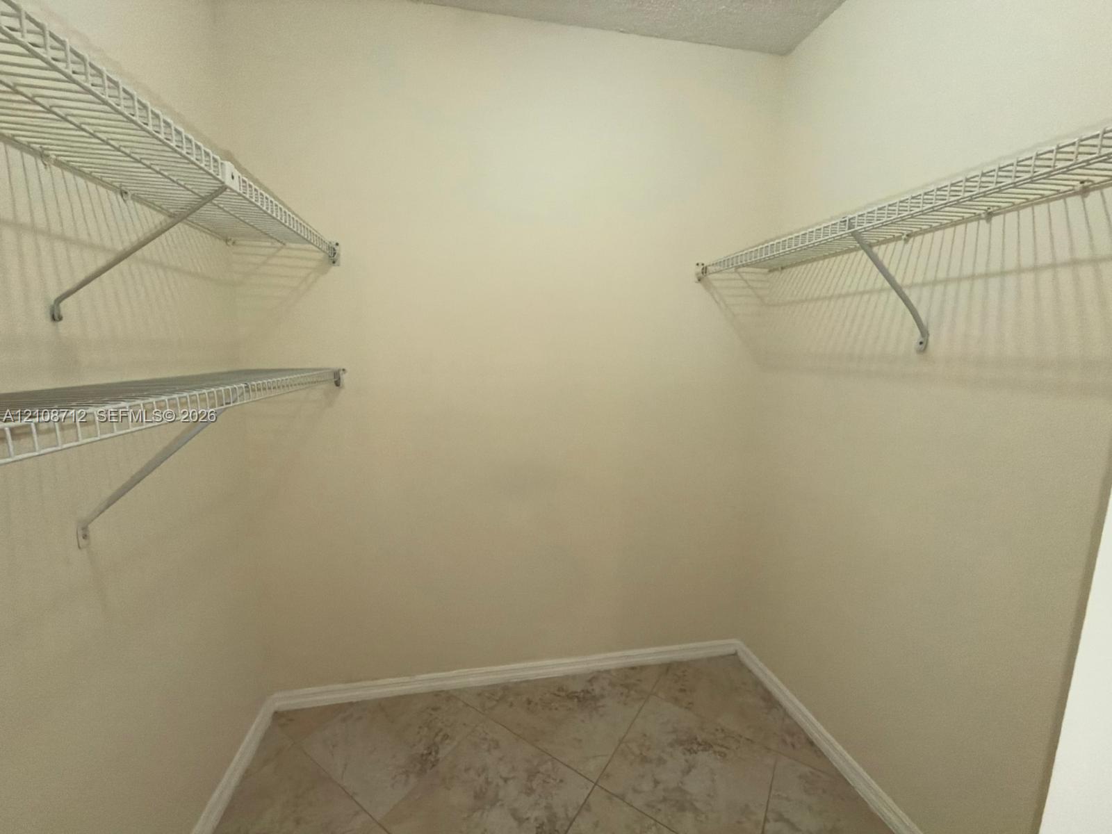 Storage area featuring neutral-toned tile flooring and wall-mounted wire shelving units