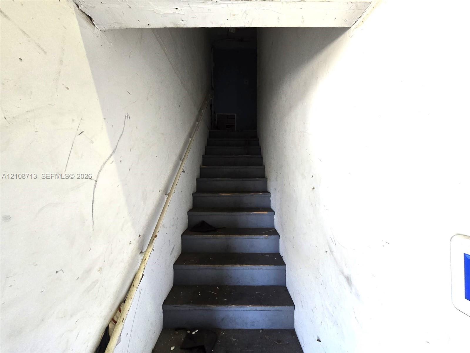 Staircase featuring painted wood treads and a mounted handrail