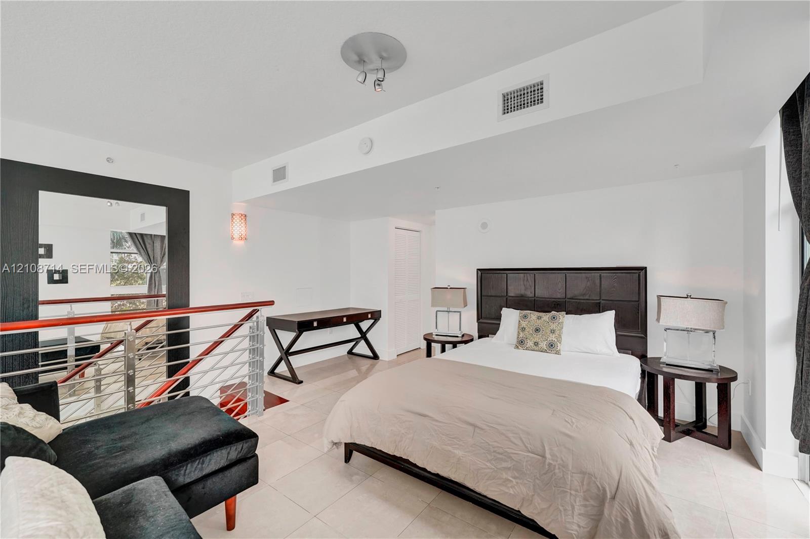 Open-plan interior featuring large-format tile flooring, metal cable railing with a wood-finish handrail, and recessed ceiling lighting