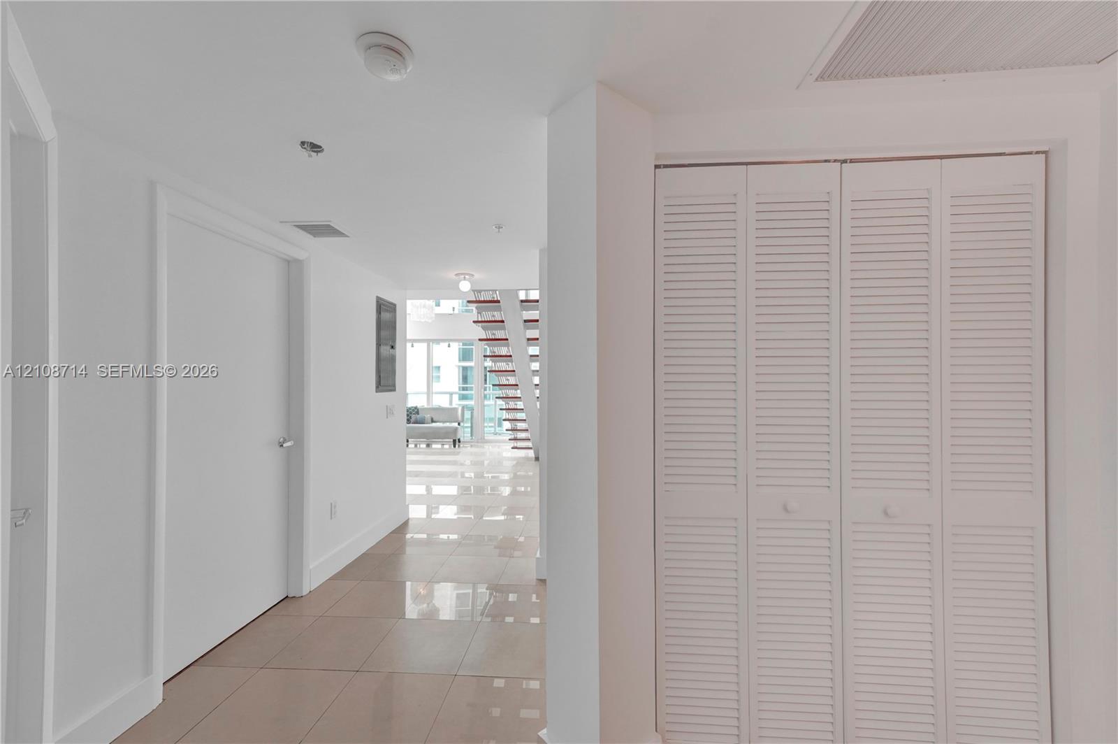 Glossy tile flooring, louvered bi-fold closet doors, and a staircase with open risers Glossy tile flooring, louvered bi-fold closet doors, and a staircase with open risers