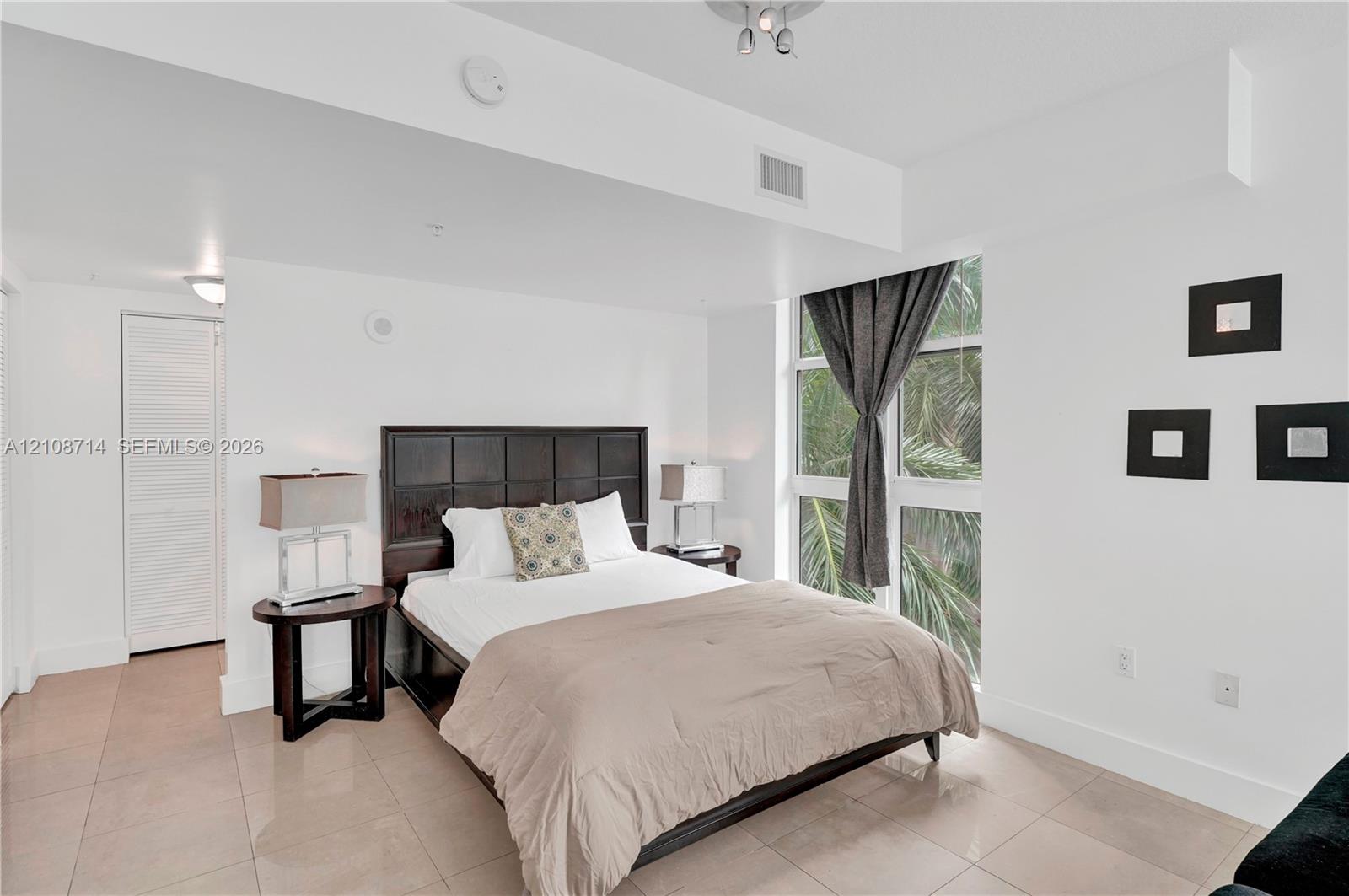 Floor-to-ceiling windows, large-format tile flooring, louvered closet doors, and recessed ceiling lighting