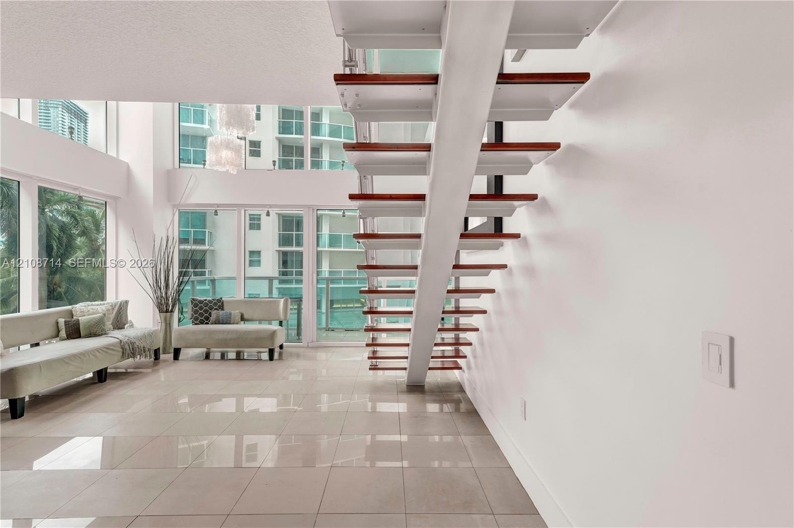 Floating staircase featuring wood treads and white stringers, floor-to-ceiling windows, and tile flooring Floating staircase featuring wood treads and white stringers, floor-to-ceiling windows, and tile flooring