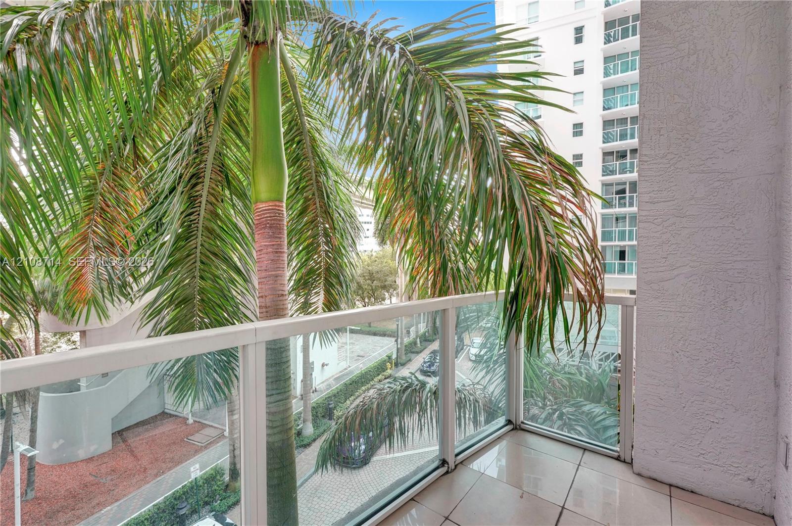 Private balcony featuring tile flooring and a glass-paneled railing