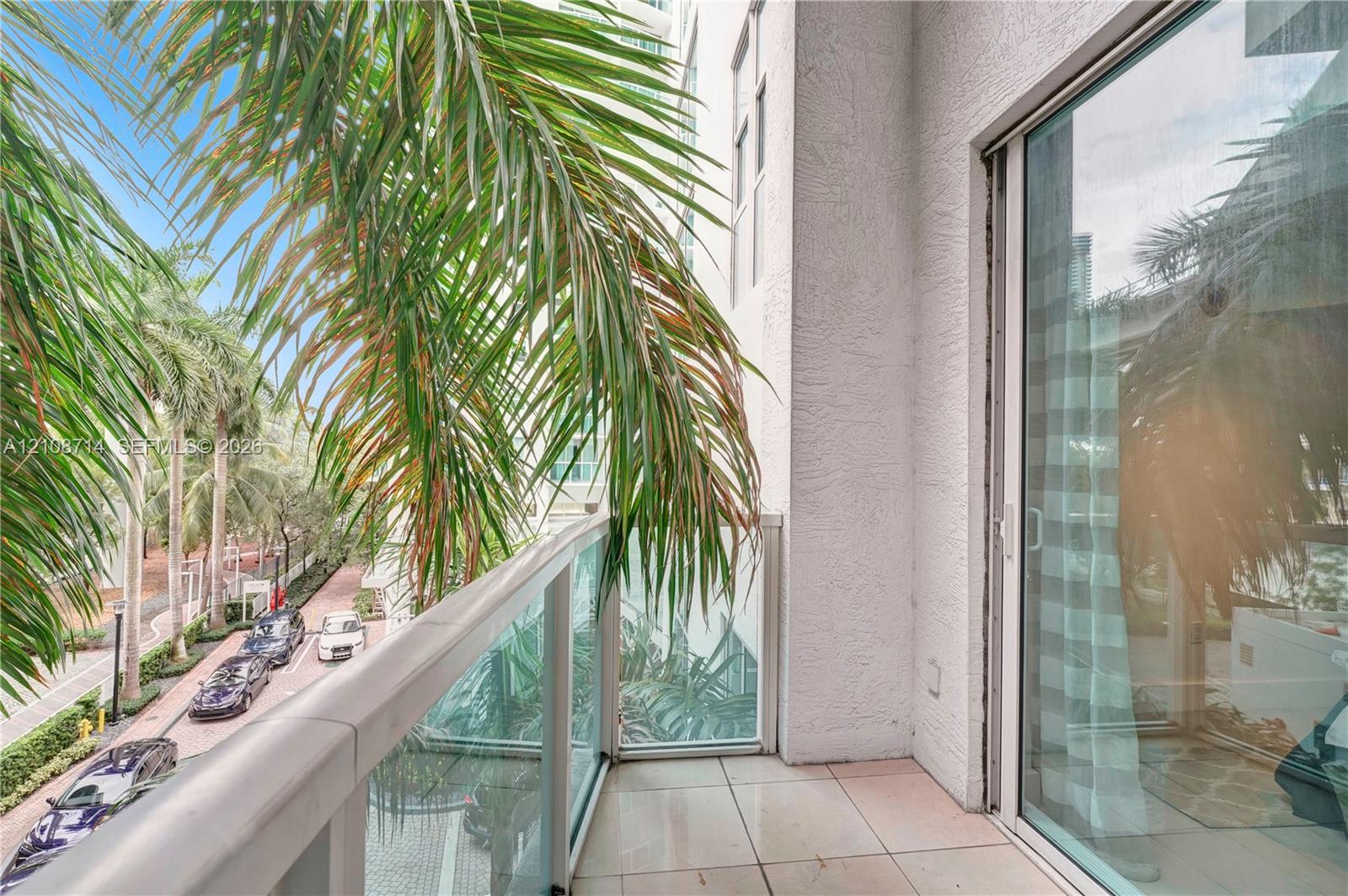Private balcony featuring tile flooring and a glass railing with a metal frame, accessed by a sliding glass door
