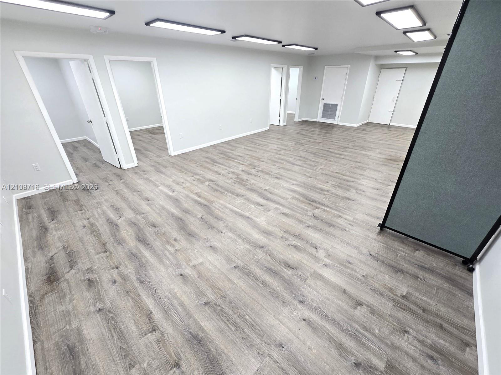 Open-concept interior featuring wood-finish flooring, neutral walls, and recessed panel lighting
