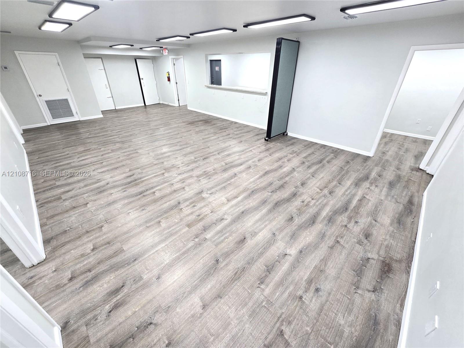 Open-concept interior featuring wood-finish flooring, recessed lighting fixtures, and a service pass-through window