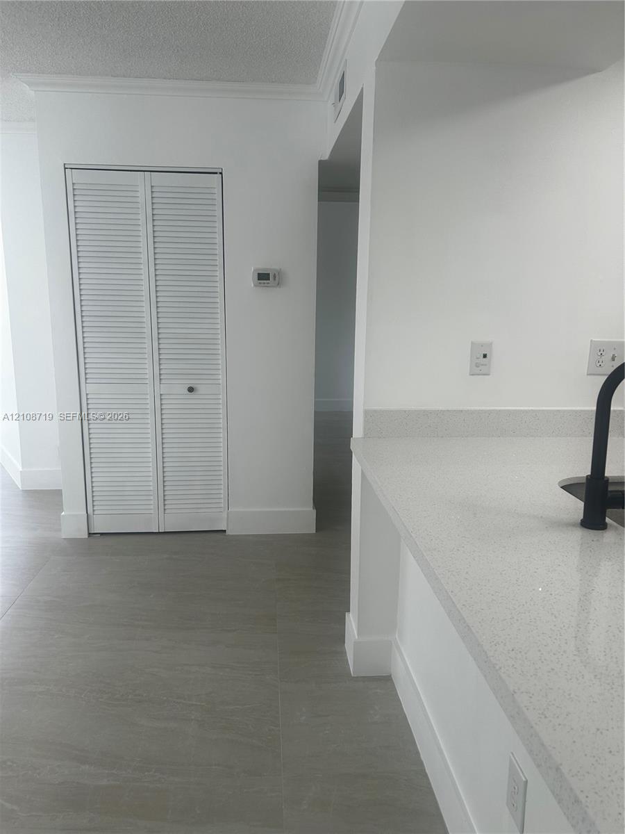 Neutral-toned tile flooring, quartz countertops, matte black faucet, and white louvered-door closet Neutral-toned tile flooring, quartz countertops, matte black faucet, and white louvered-door closet
