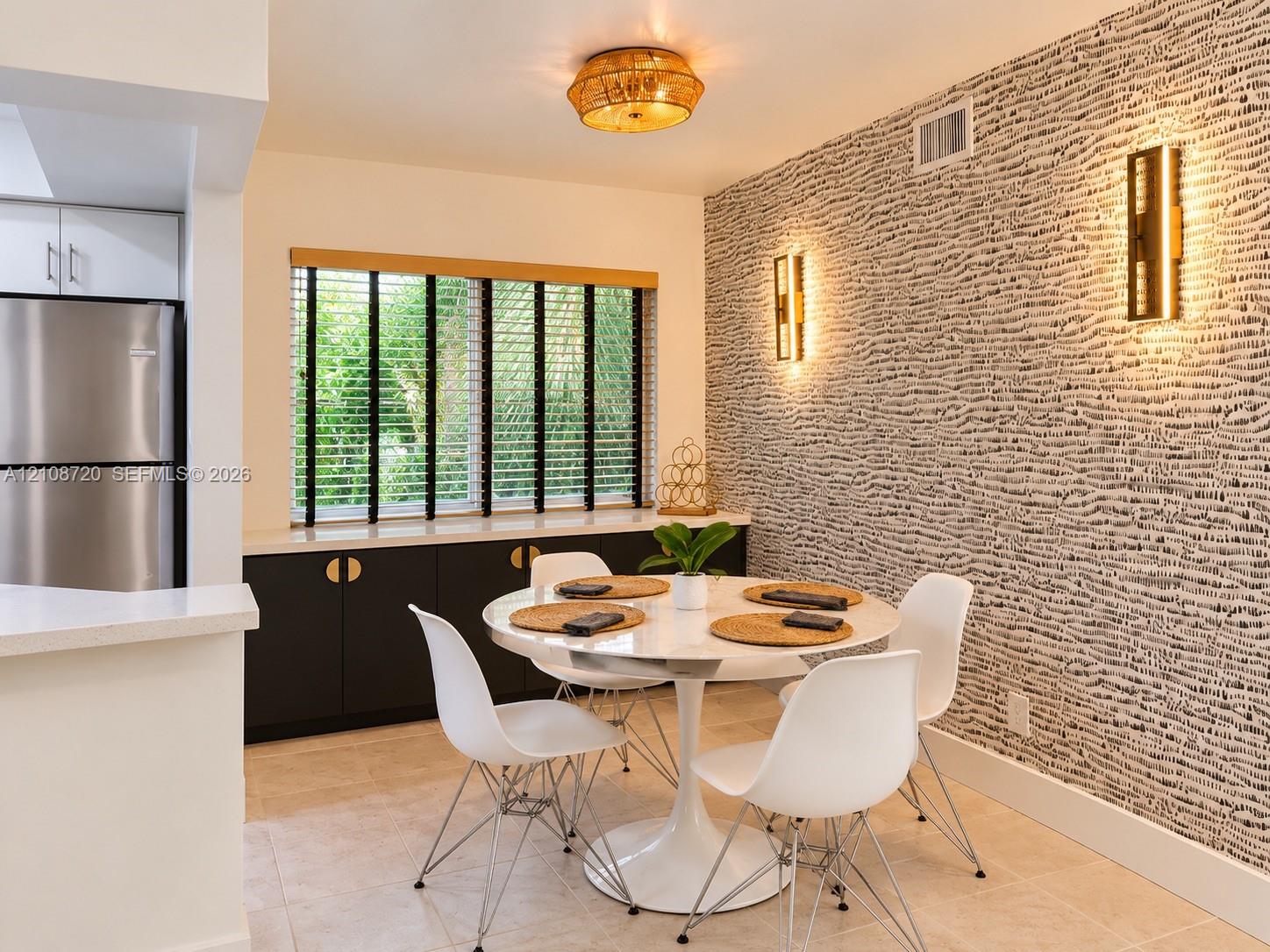 Dining area featuring a statement textured accent wall, built-in cabinetry with metallic hardware, dual wall-mounted light fixtures, and a flush-mount overhead light Dining area featuring a statement textured accent wall, built-in cabinetry with metallic hardware, dual wall-mounted light fixtures, and a flush-mount overhead light
