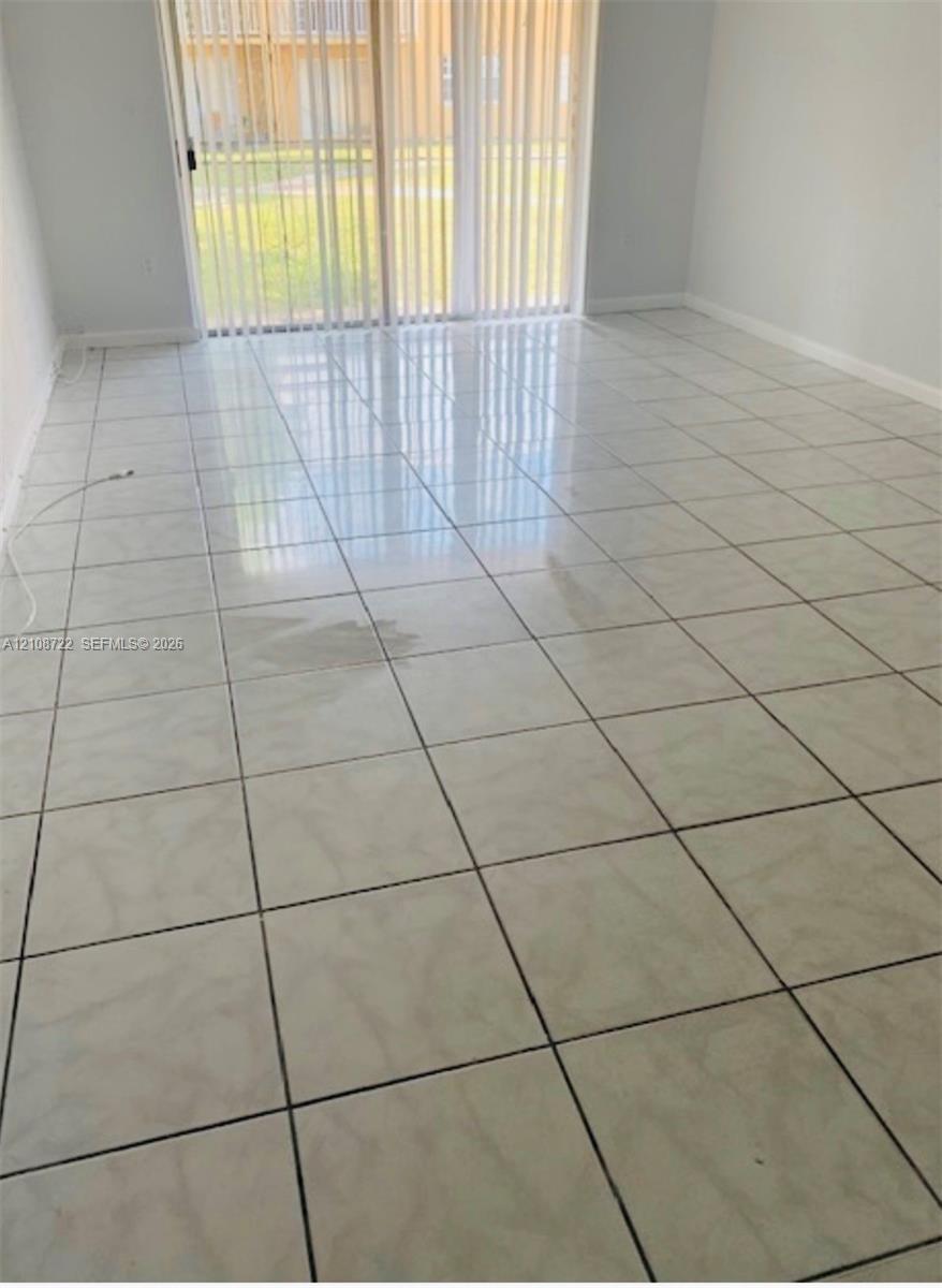 Large-format square tile flooring, vertical window blinds, and sliding glass door Large-format square tile flooring, vertical window blinds, and sliding glass door
