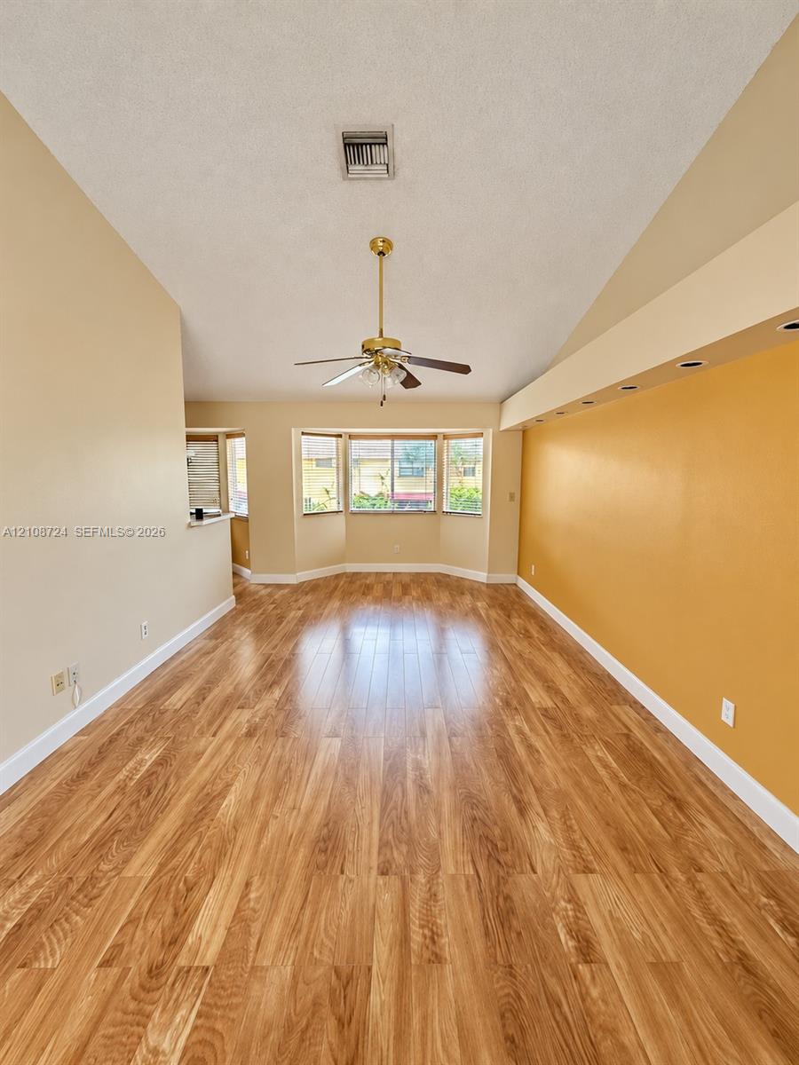 Vaulted ceilings, wood-finish flooring, recessed lighting, and a bay window