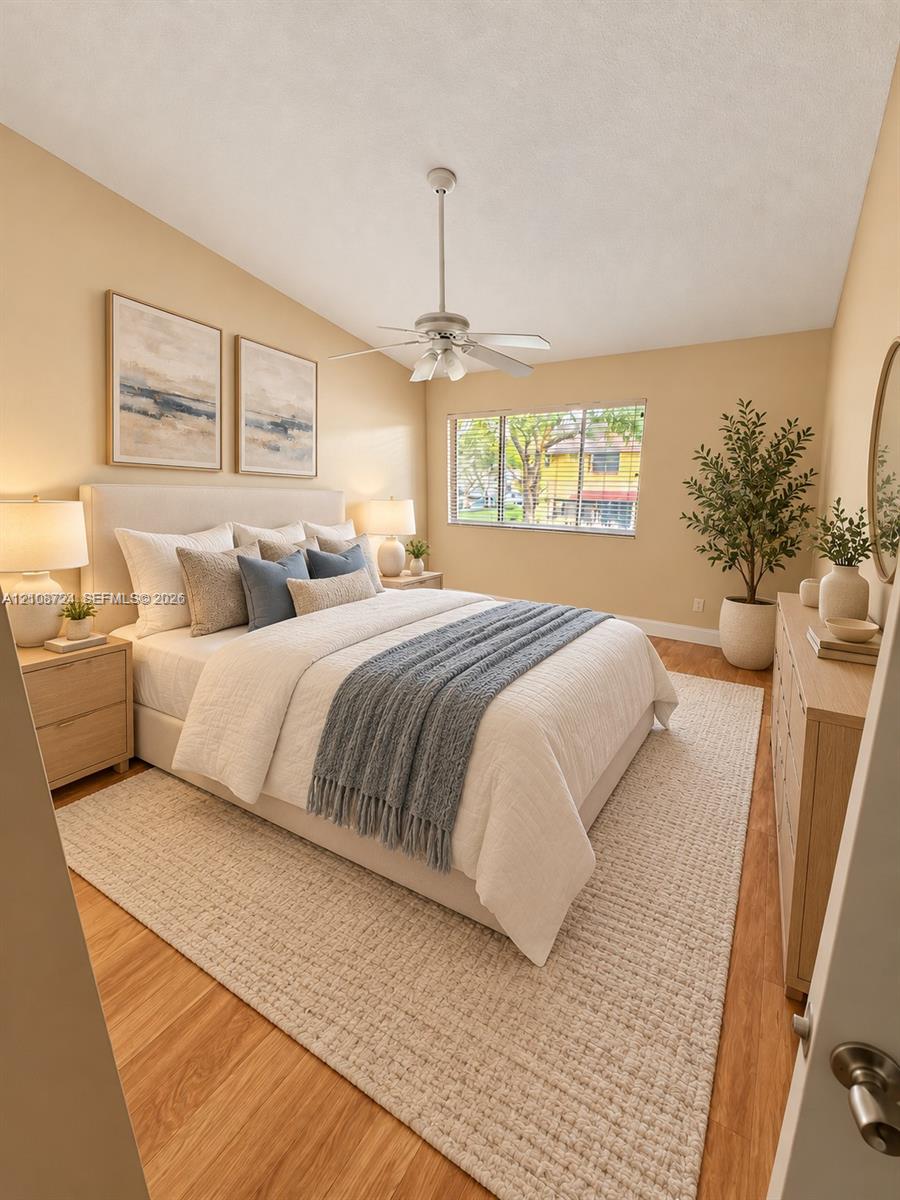 Room featuring wood-finish flooring, a multi-blade ceiling fan with integrated lighting, and a large window