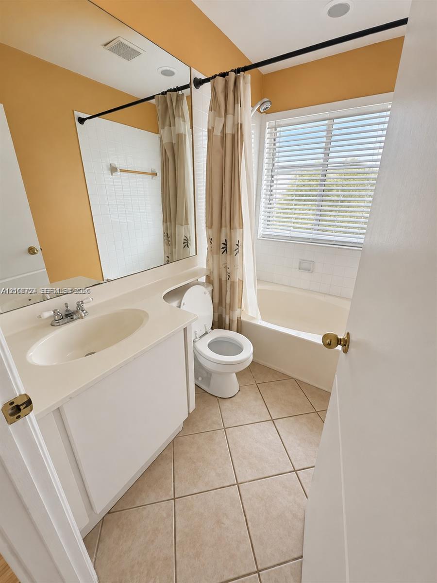 Bathroom featuring a vanity with an integrated countertop sink, a full-width wall mirror, a ceramic tile bathtub surround, and diagonal-set floor tiling
