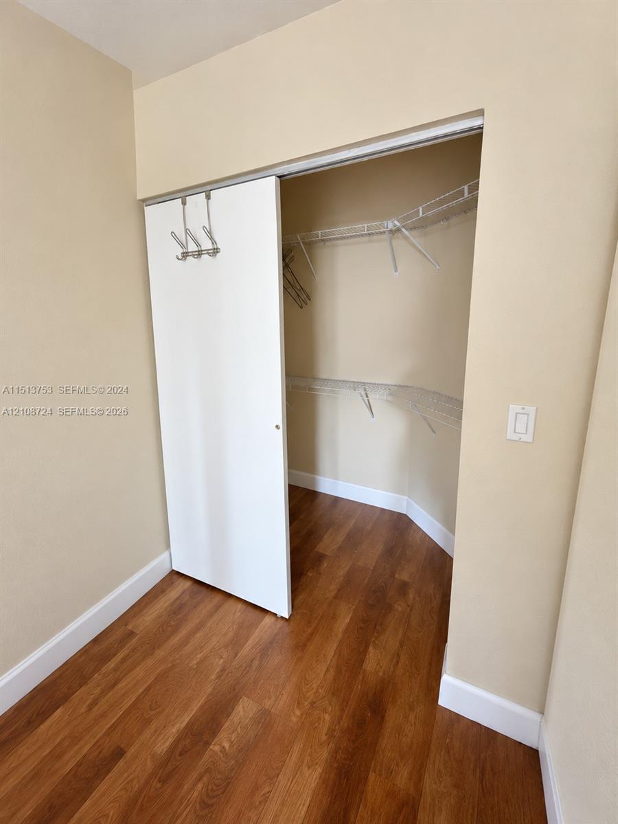 Walk-in closet featuring wood-finish flooring, white sliding door, and multi-tier wire shelving