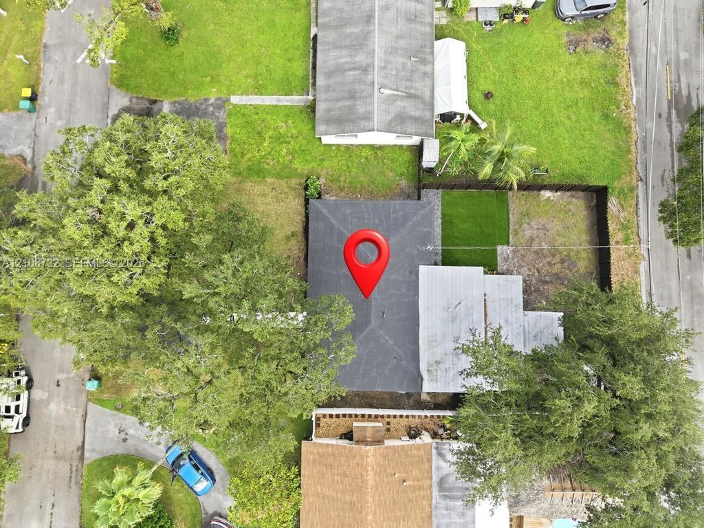 Aerial perspective of property lot featuring mature trees, fenced perimeter, and maintained grass areas