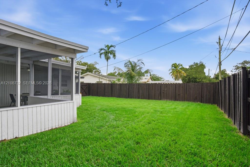 Screened-in porch featuring vertical siding, level grassy lawn, and privacy fencing