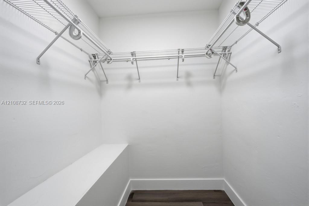 Storage area featuring white wire shelving, a built-in bench, and wood-finish flooring