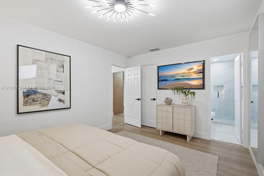 Multi-panel six-door interior doors with matte black hardware, wood-finish flooring, and contemporary sunburst-style ceiling light fixture