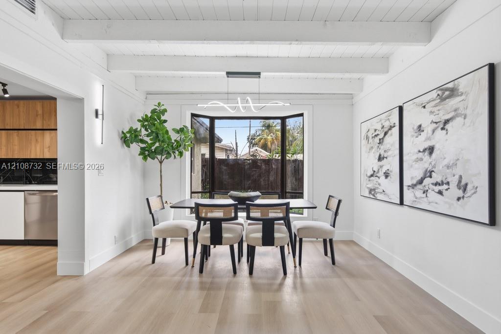 Dining area featuring exposed ceiling beams, wood-finish flooring, a large bay window, and a modern geometric pendant light fixture