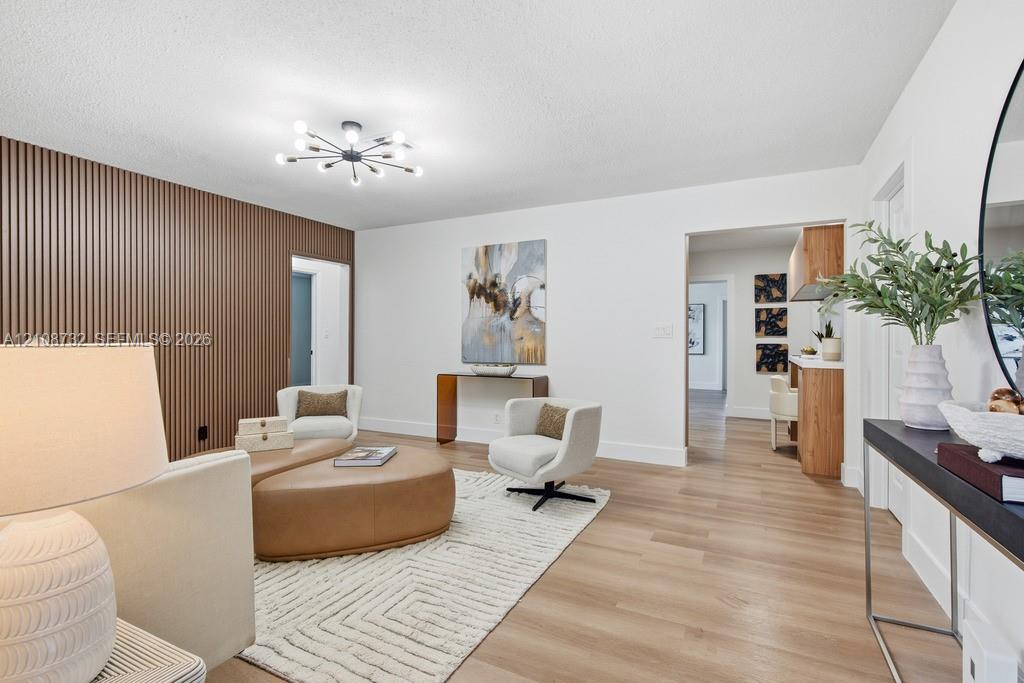 Living area featuring wood-finish flooring, a decorative slatted wood accent wall, and a multi-arm sputnik-style ceiling fixture