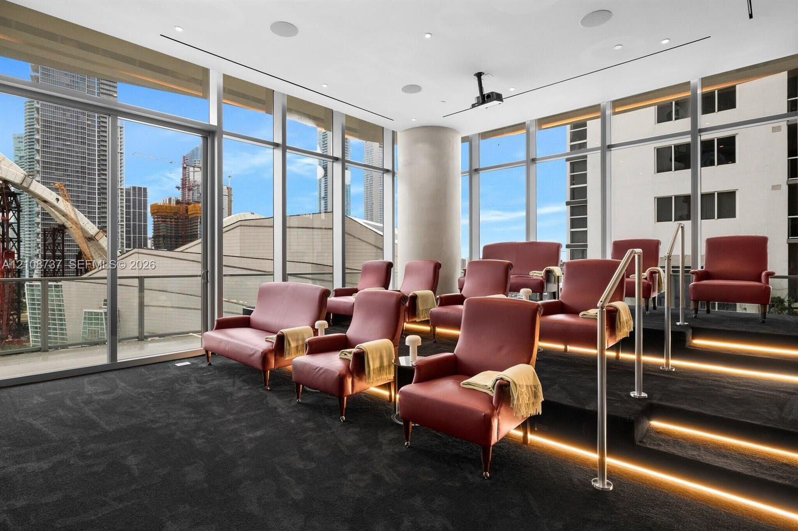 Floor-to-ceiling windows, tiered seating platform with integrated LED stair lighting, built-in ceiling projector, and recessed surround sound speakers