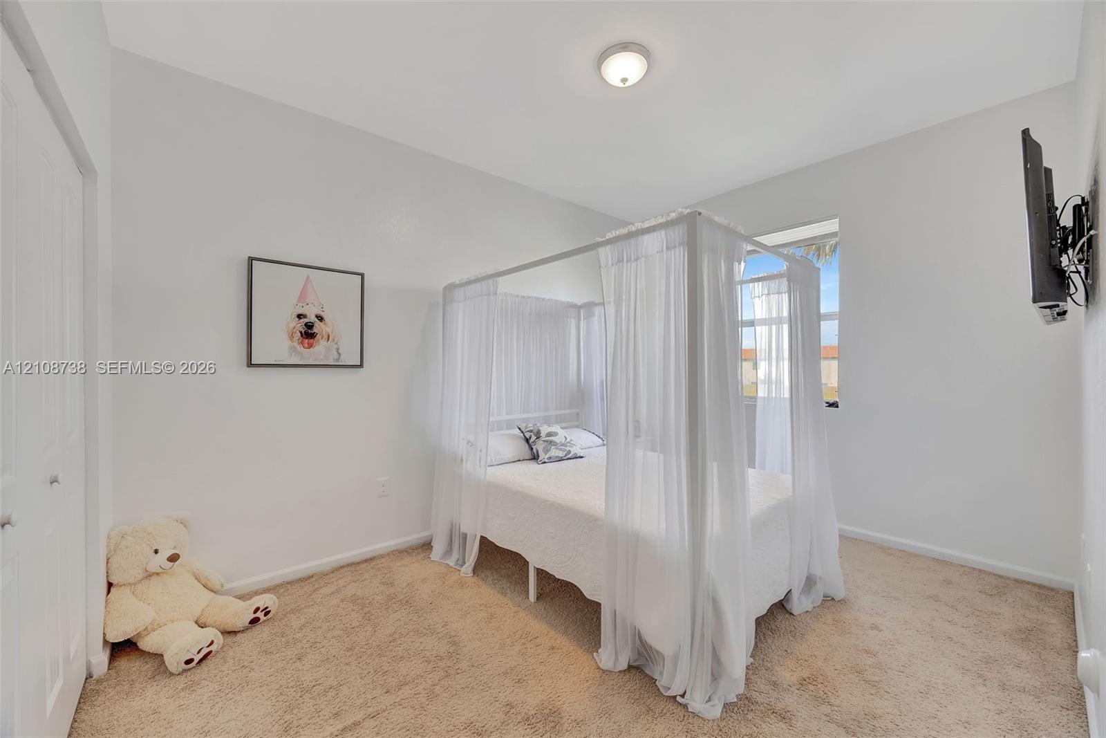 Neutral-toned bedroom featuring carpeted flooring, a single window, and a white interior door