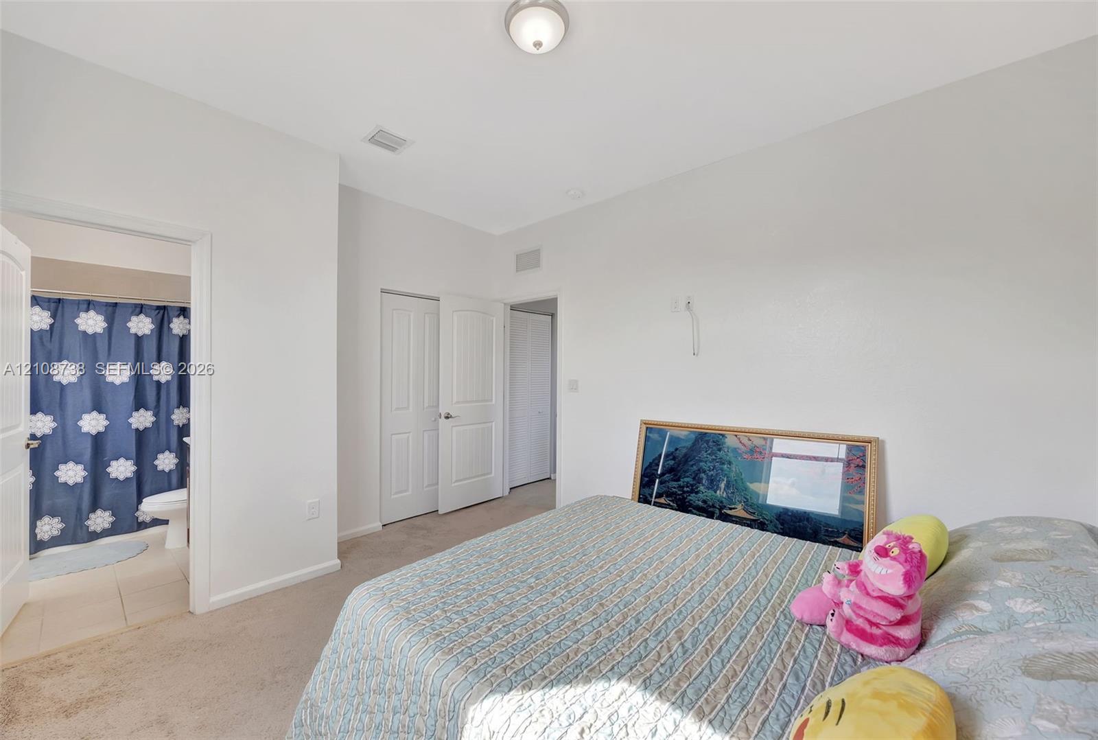 Neutral-toned interior space featuring carpeting, white paneled doors, and a flush-mount ceiling light fixture