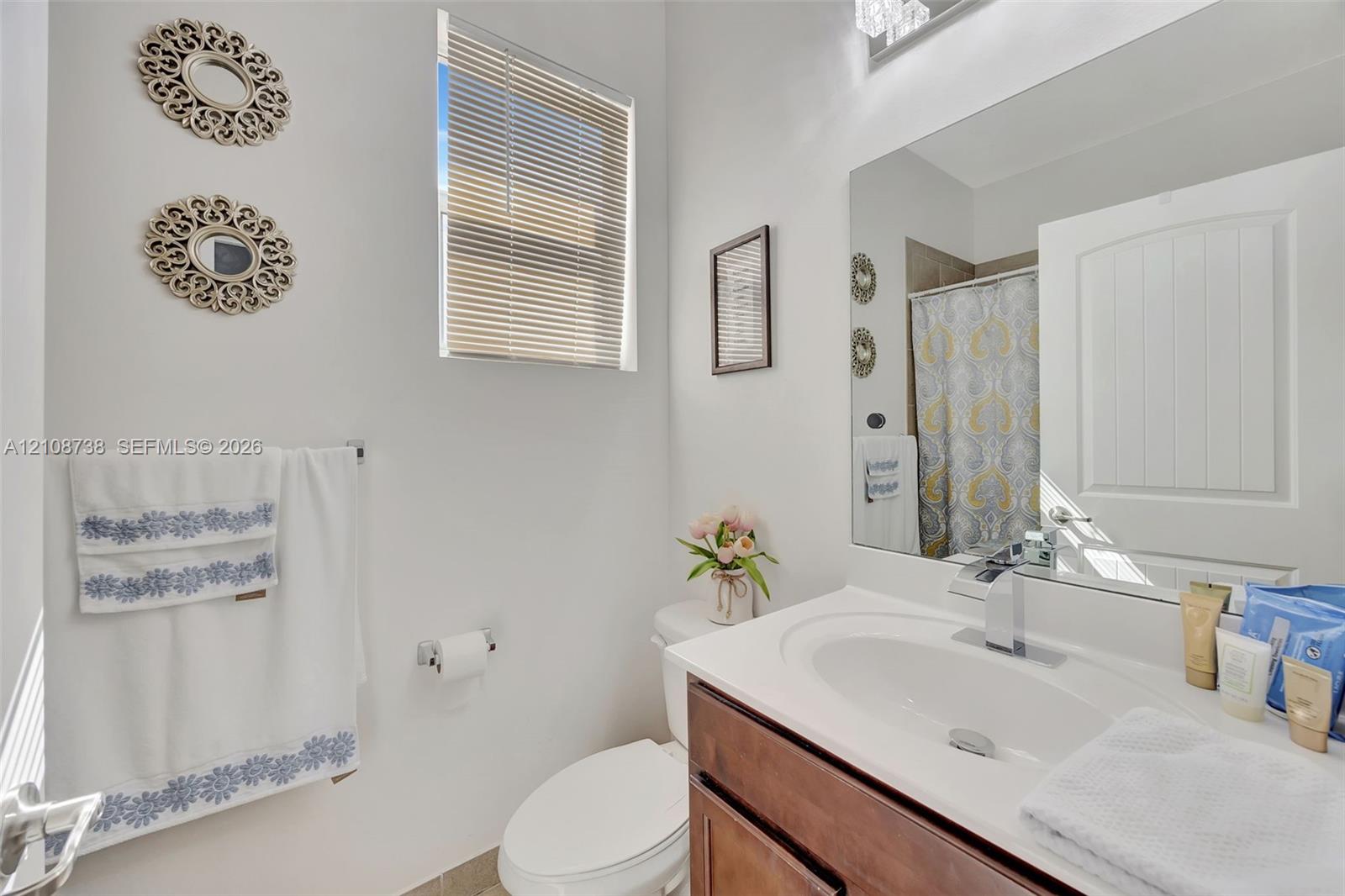 Bathroom featuring a wood-finish vanity with a white countertop and integrated sink, chrome-finish faucet, and a large wall-mounted mirror