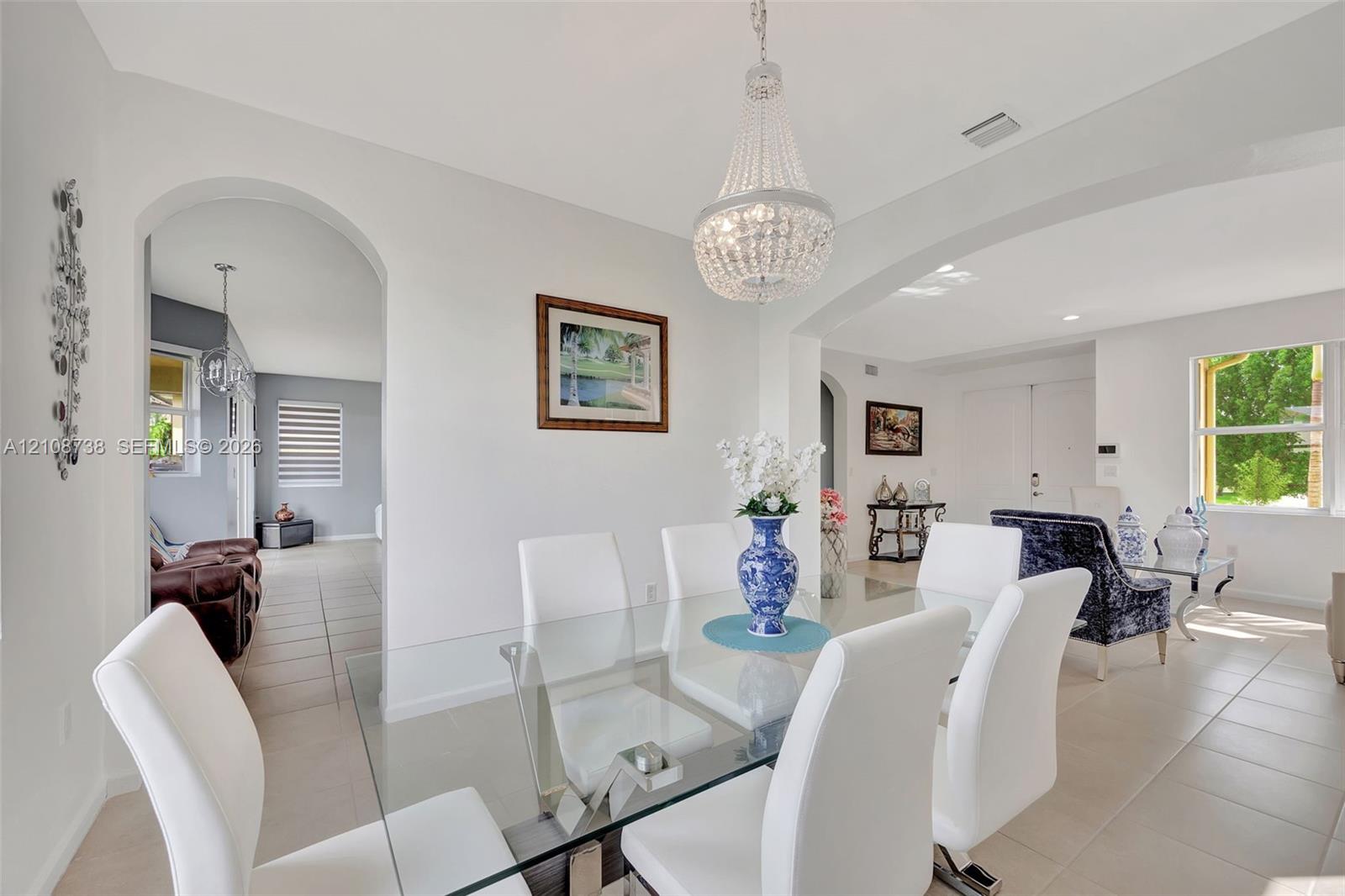 Open concept interior featuring arched wall openings, neutral tile flooring, and a crystal chandelier