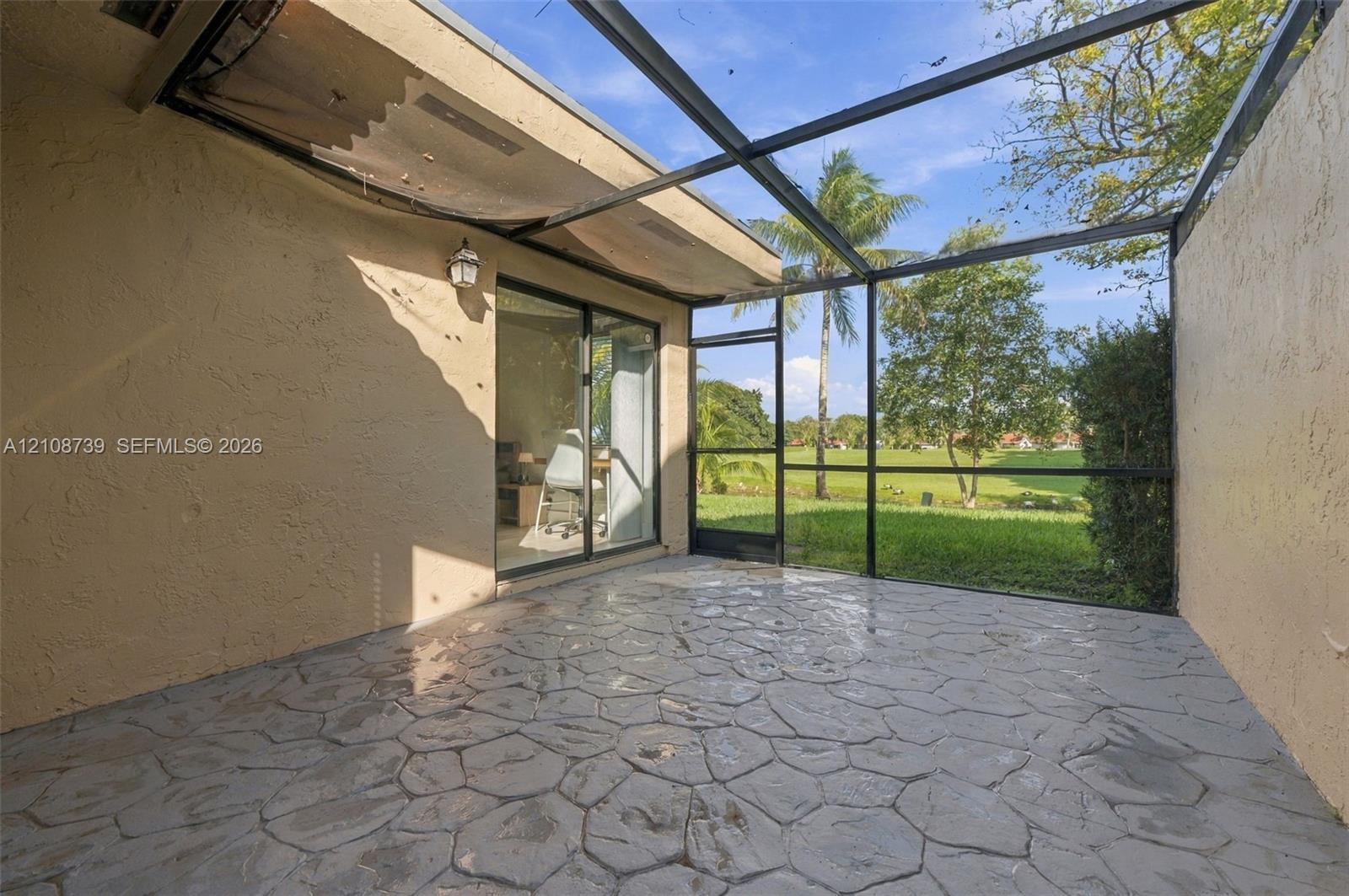 Enclosed lanai featuring a stamped concrete patio, black metal screening, and sliding glass door entry