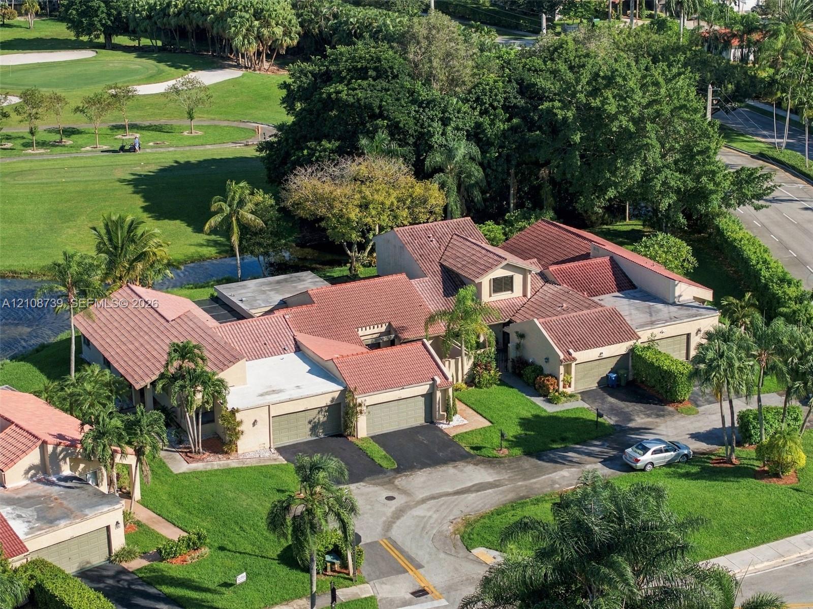 Multi-structure residential property featuring terracotta-style roofing, stucco exterior, dual attached garages, and expansive manicured grounds with mature tropical landscaping