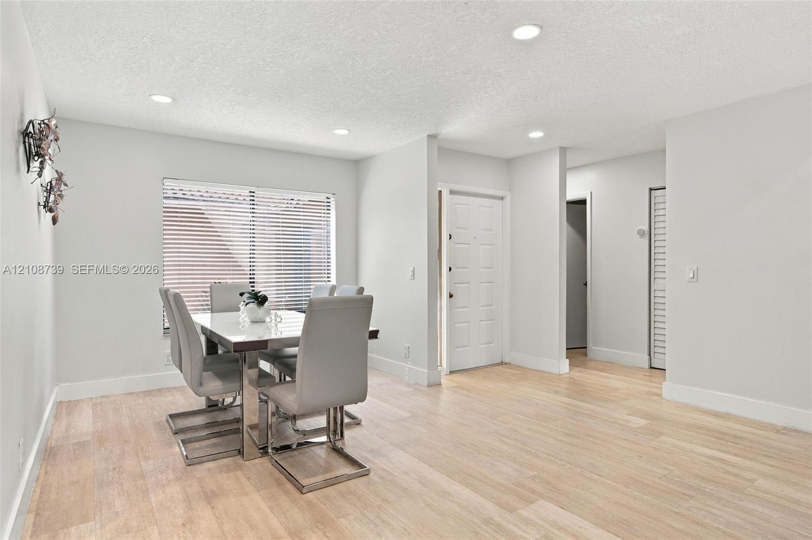 Open living space featuring wood-finish flooring, recessed lighting, and a multi-panel entry door