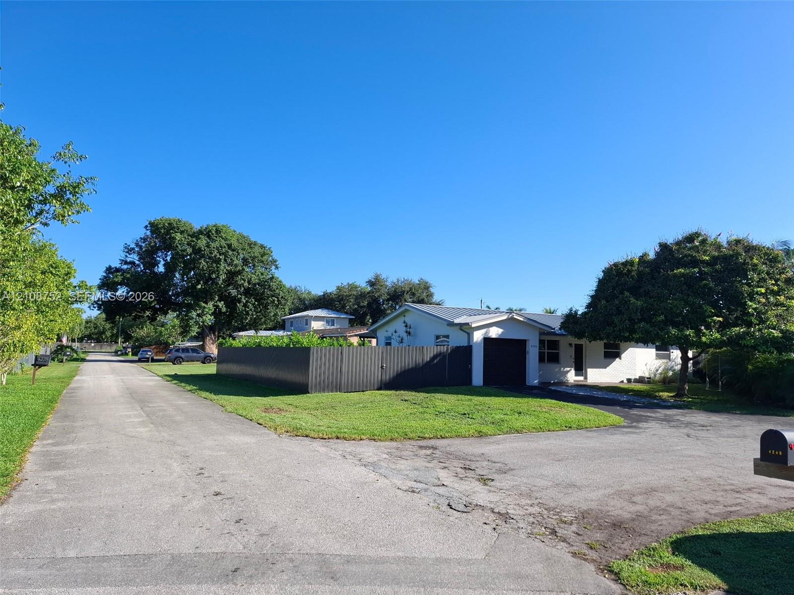 Single-story exterior featuring a metal roof, an attached garage, and a fenced-in side yard situated on a corner lot with paved driveway access