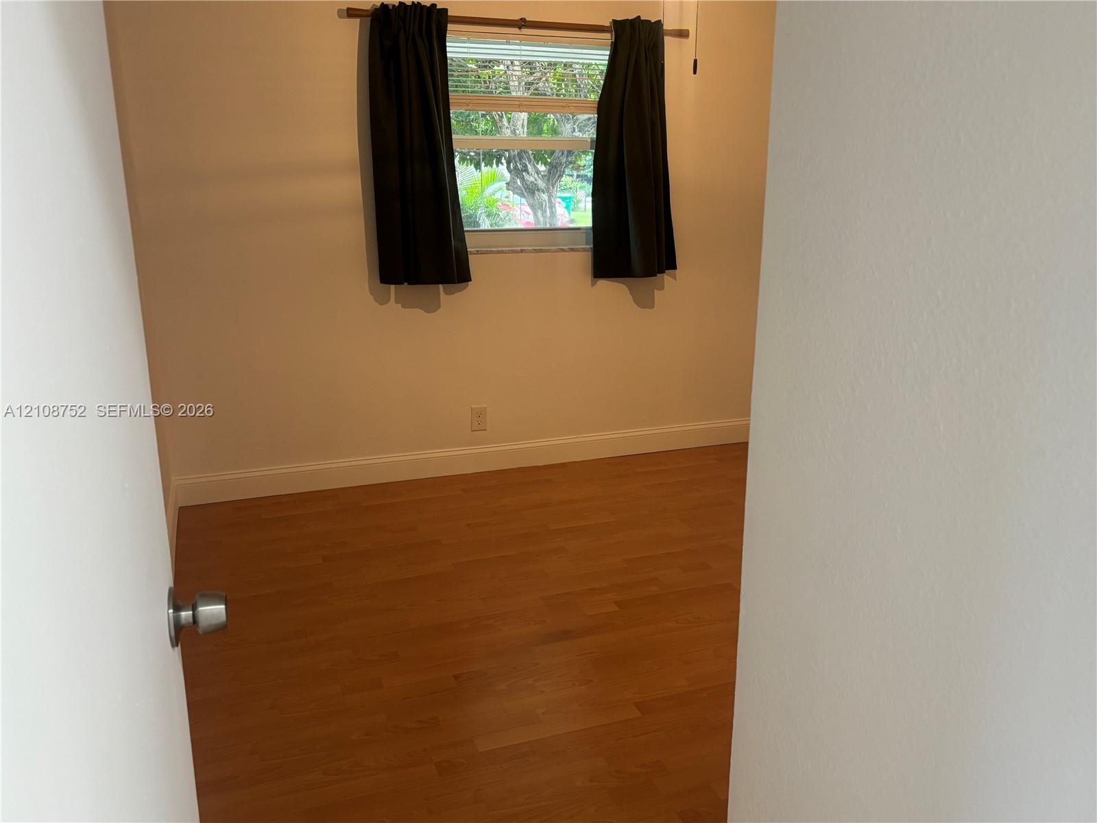 Room featuring wood-finish flooring, neutral-toned walls, and a horizontal sliding window