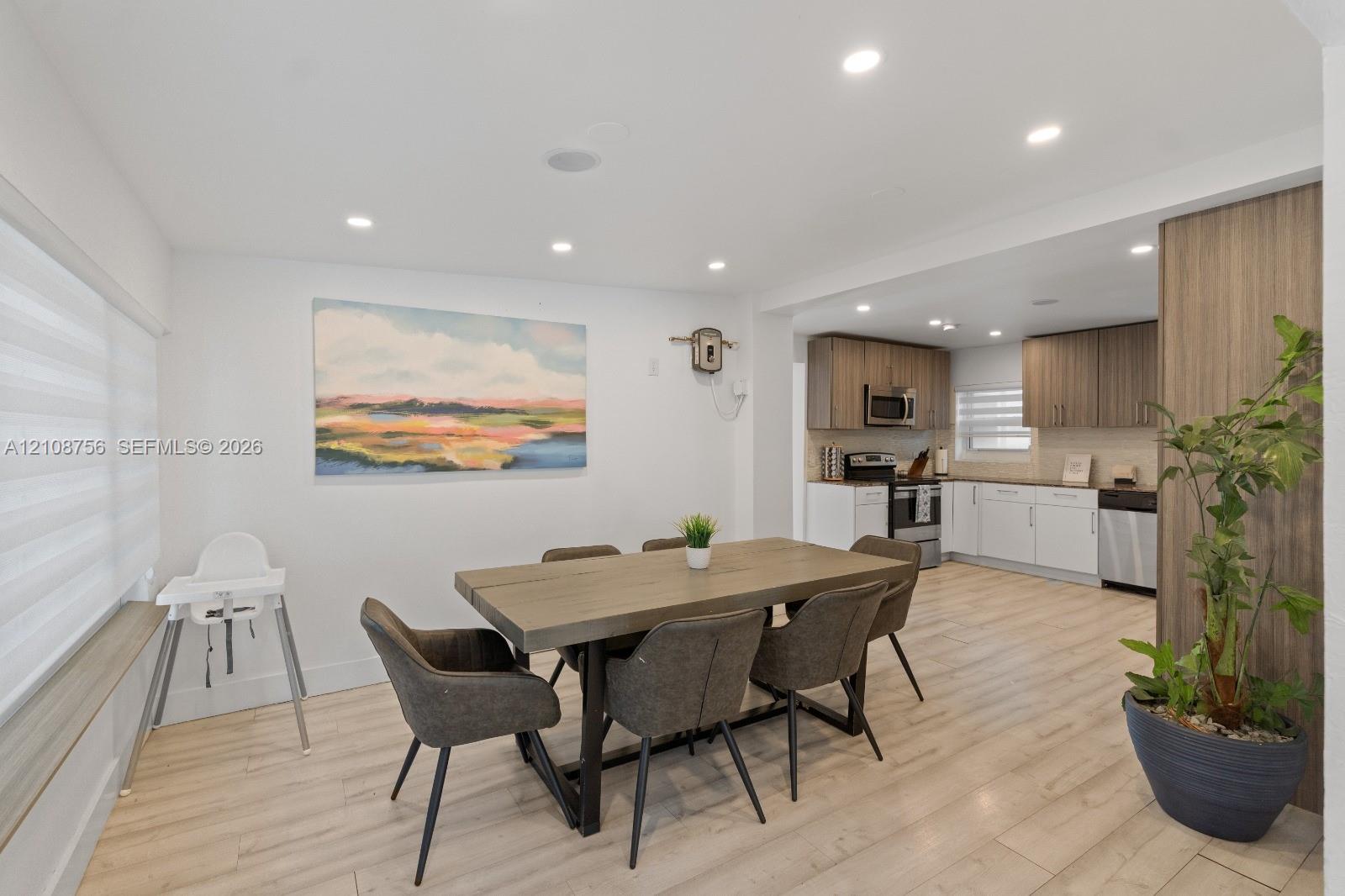 Kitchen featuring white cabinetry, wood-finish upper cabinets, stainless steel appliances, and recessed lighting, with wood-finish flooring extending into the dining area
