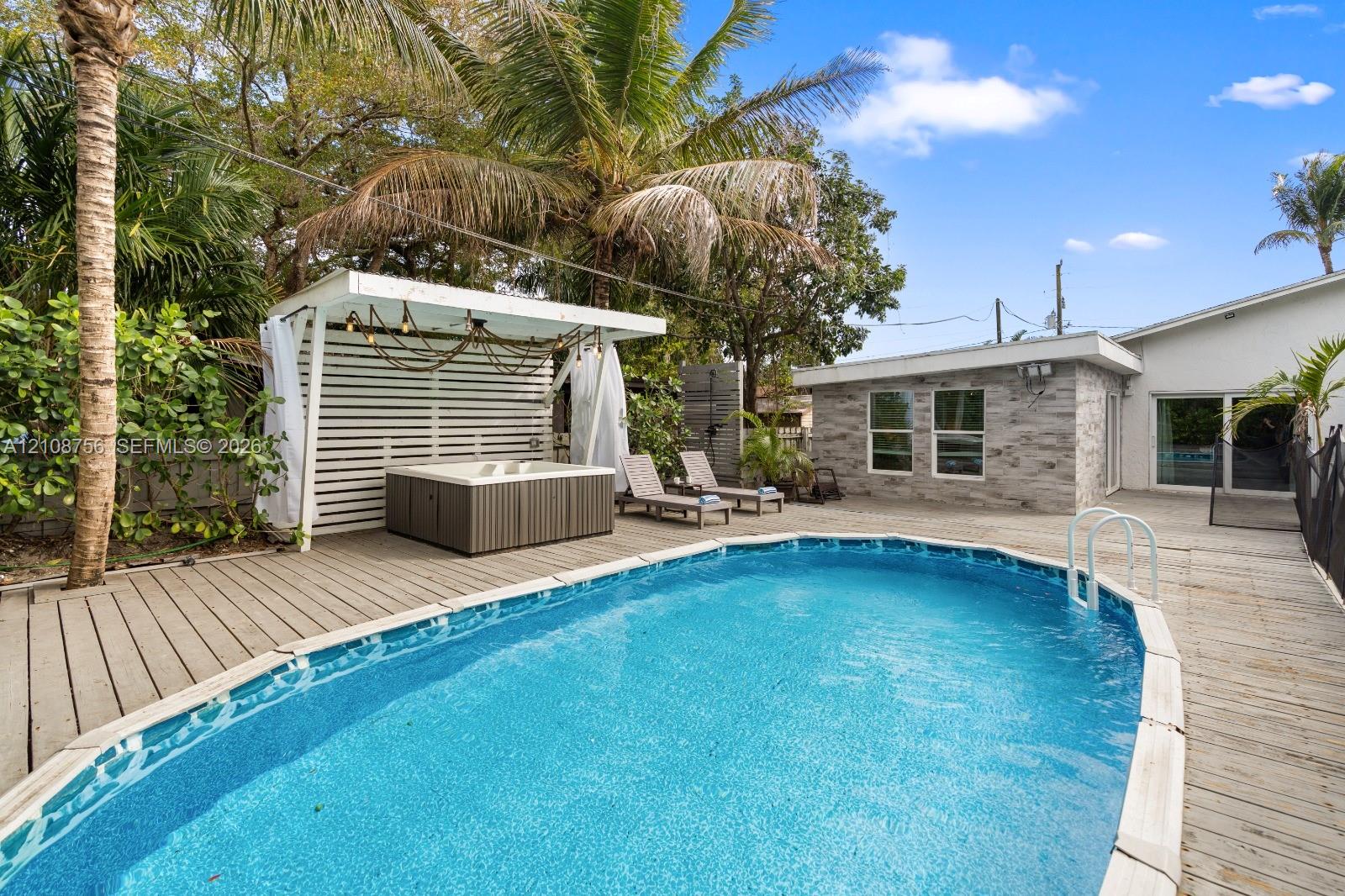 Backyard area featuring an in-ground swimming pool, wood-finished decking, and a covered pavilion with a built-in hot tub Backyard area featuring an in-ground swimming pool, wood-finished decking, and a covered pavilion with a built-in hot tub