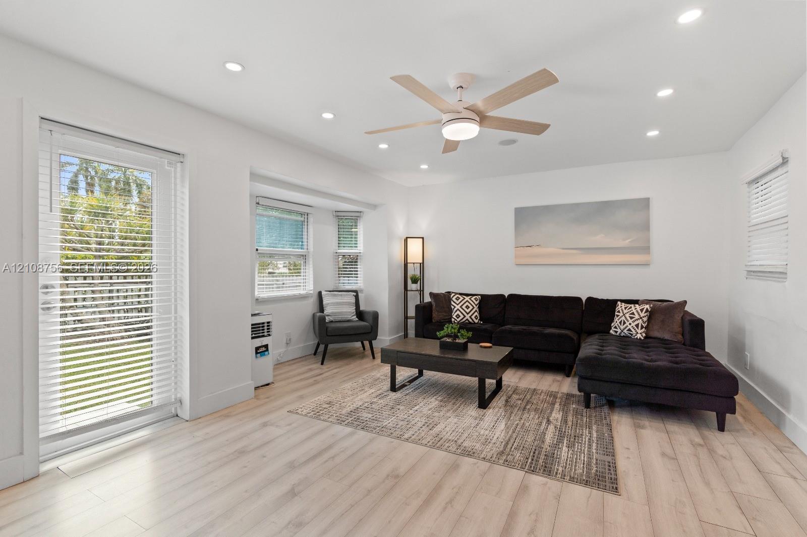 Interior space featuring wood-finish flooring, recessed lighting, a multi-blade ceiling fan with integrated light, a bay window, and a full-light glass door