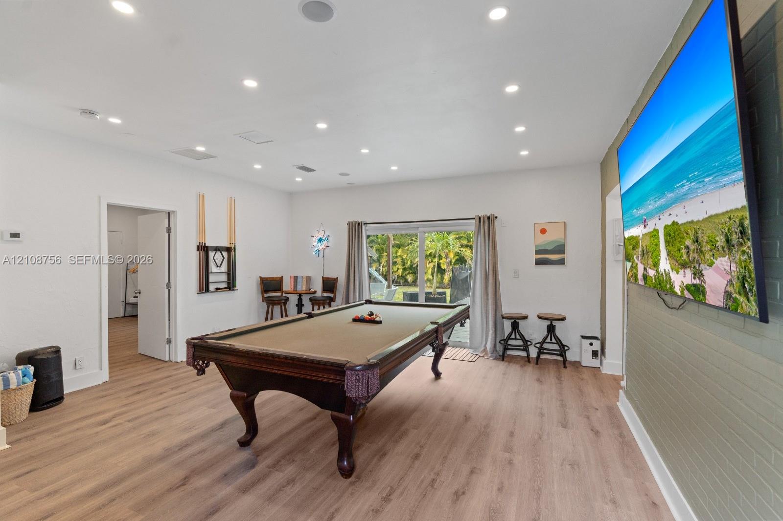 Recessed ceiling lighting, wood-finish flooring, sliding glass patio doors, and a decorative interior brick accent wall