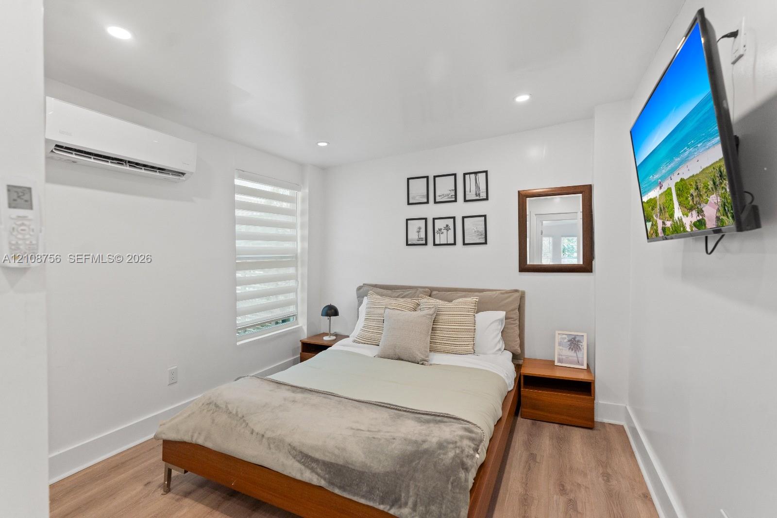 Wood-finish flooring, recessed lighting, wall-mounted ductless climate control system, and window with adjustable roller shades