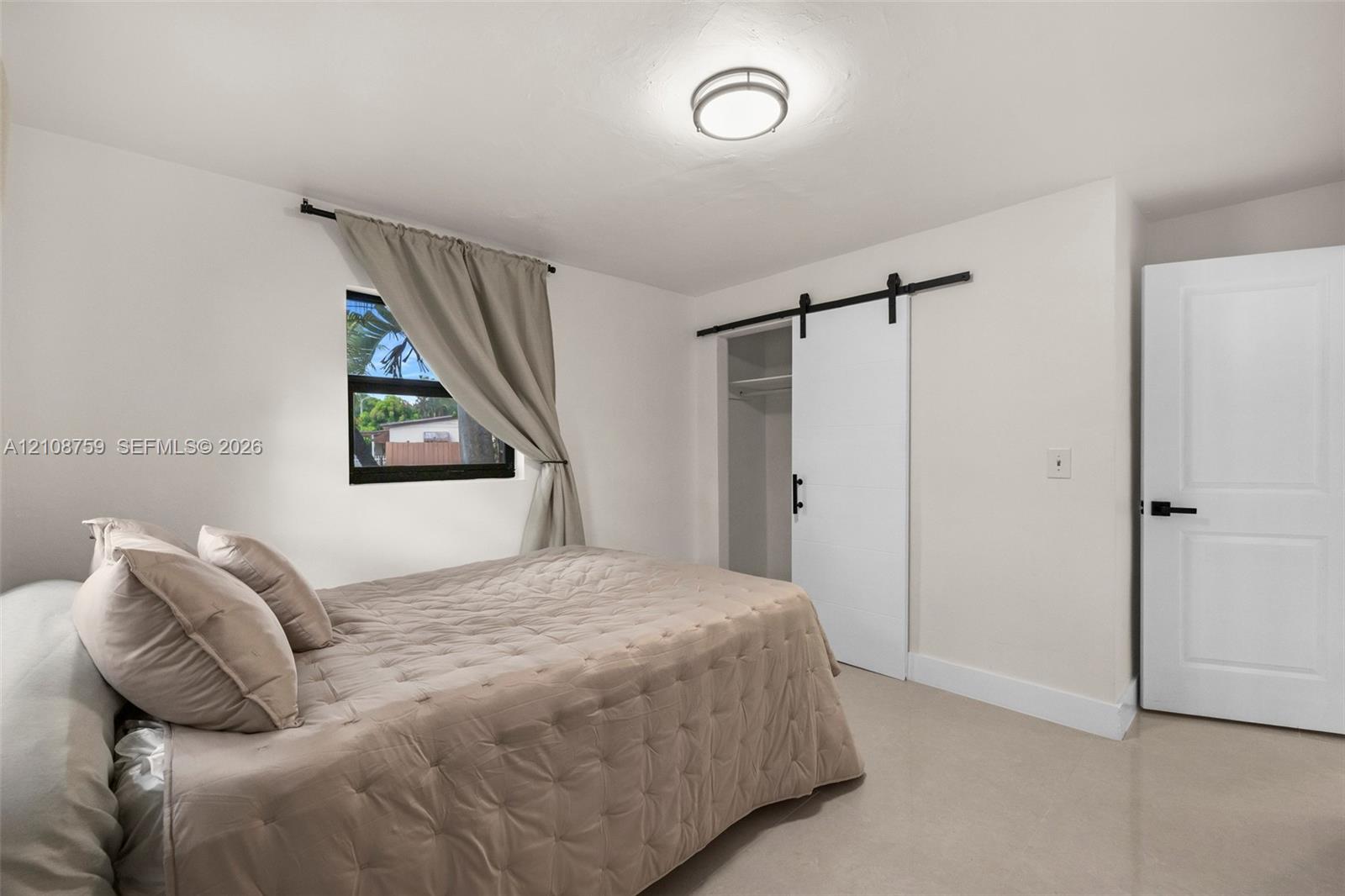 Interior space featuring a sliding barn door with black hardware, a flush-mount ceiling light fixture, neutral wall finishes, and a single-panel interior door