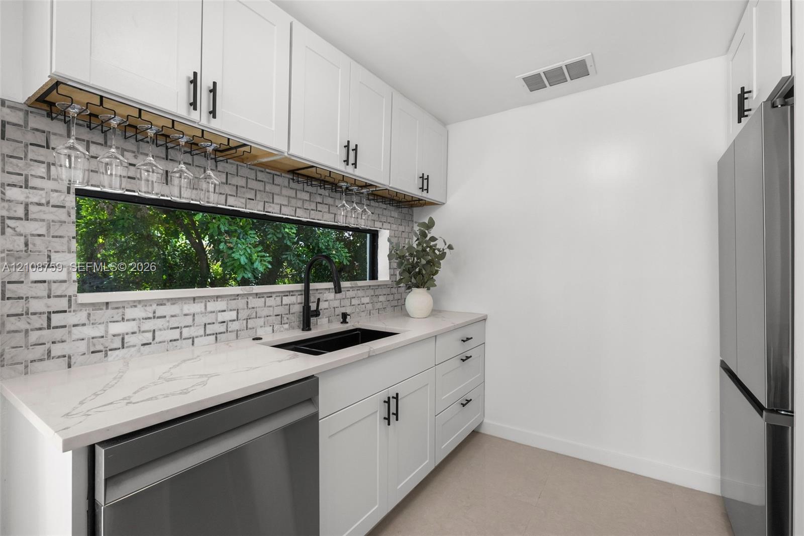 White shaker-style cabinetry, quartz countertops, horizontal brick-patterned tile backsplash, stainless steel appliances, and matte black plumbing fixtures