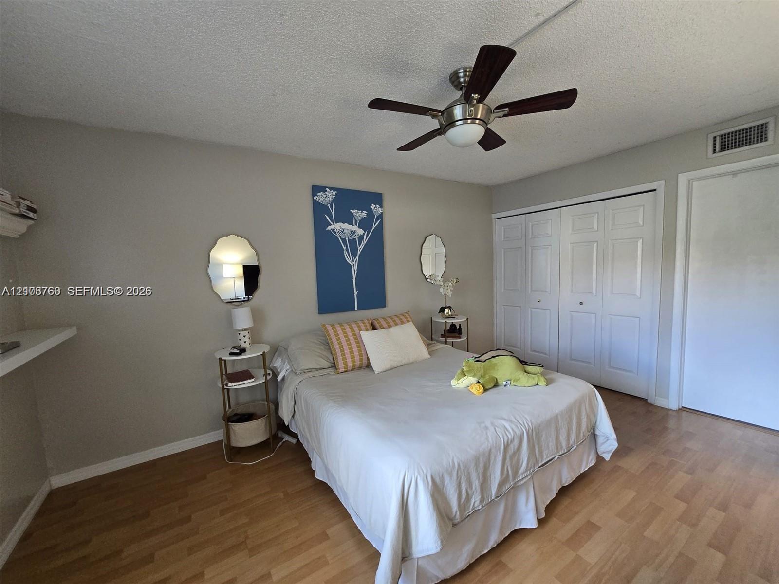 Wood-finish flooring, brushed metal ceiling fan with integrated lighting, and multi-panel sliding closet doors