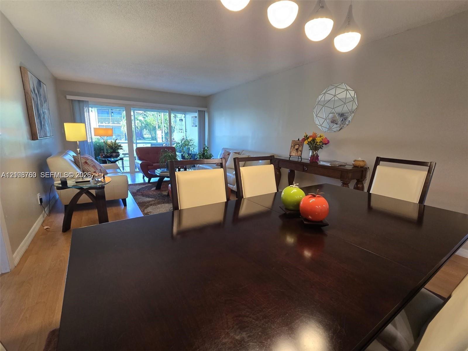 Neutral wall tones, wood-finish flooring, and a five-light pendant fixture