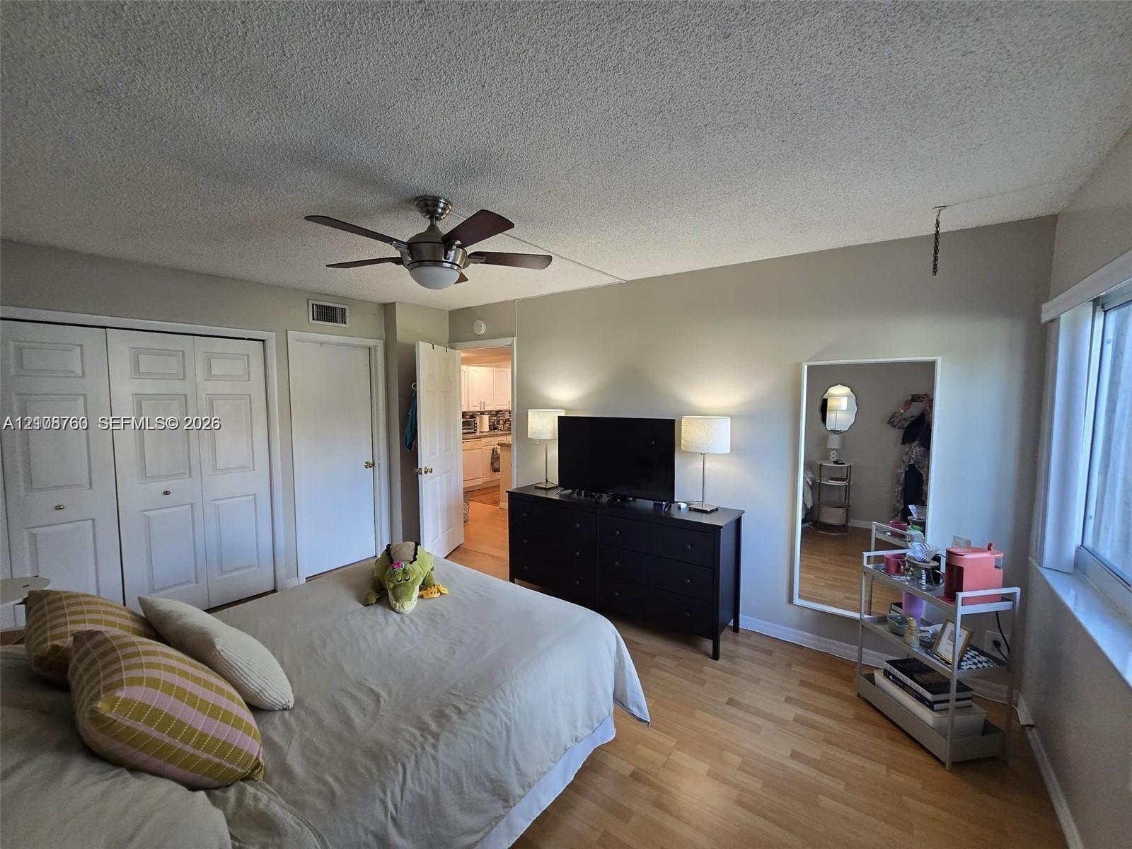 Room featuring wood-finish flooring, a ceiling fan with integrated lighting, and white multi-panel closet doors