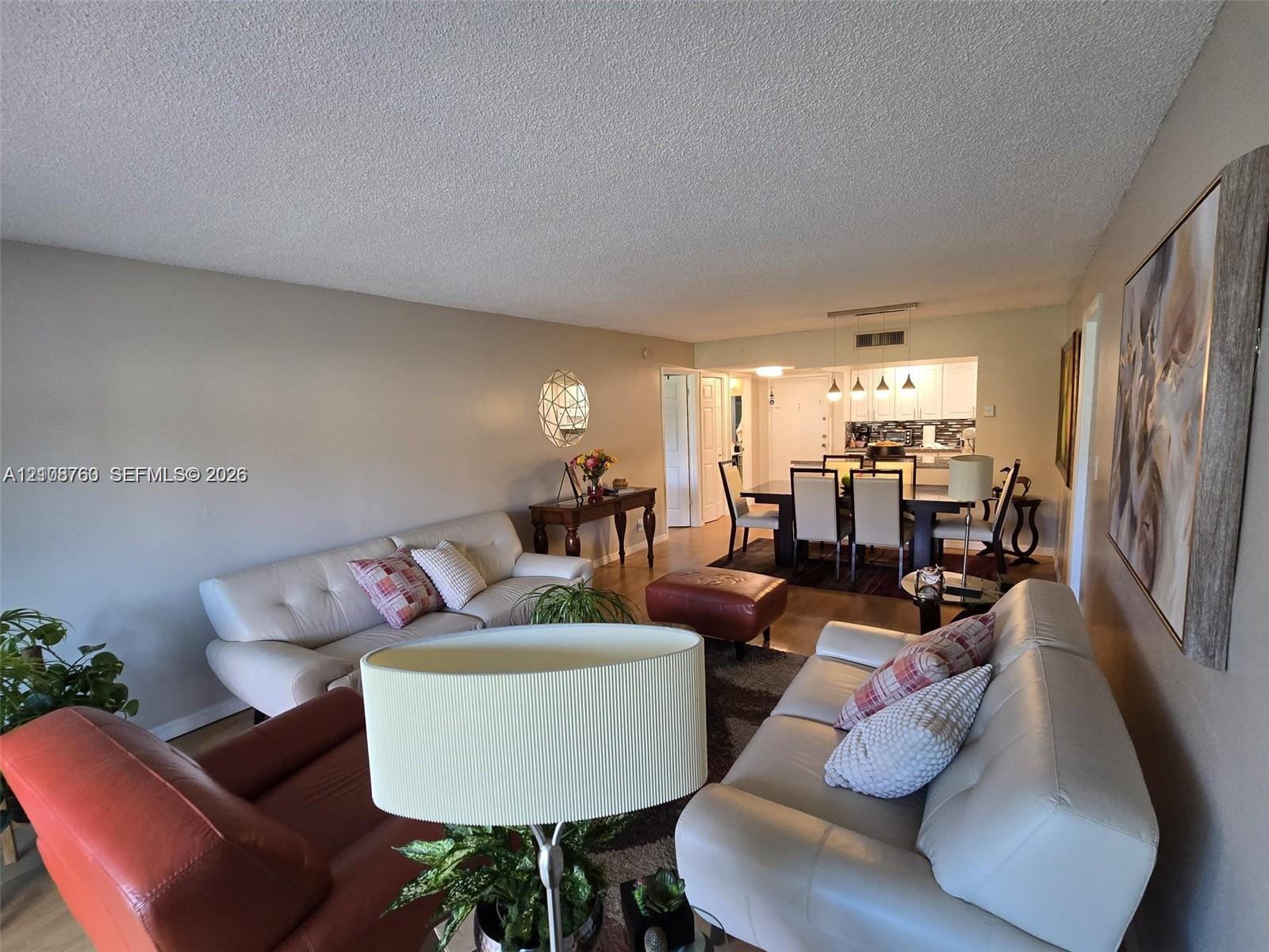Living area featuring wood-finish flooring and recessed lighting with a galley-style kitchen including white cabinetry and tiled backsplash