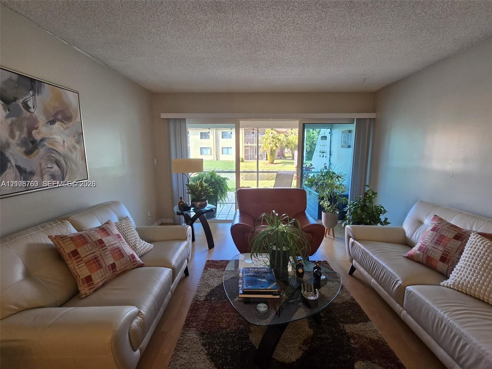 Living area featuring wood-finish flooring and large sliding glass doors leading to a screened balcony