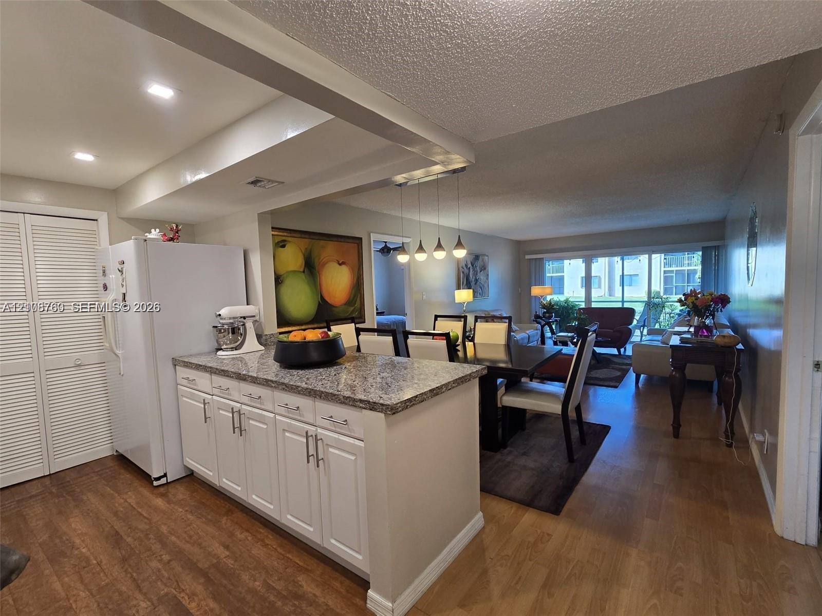 Kitchen featuring white cabinetry, stone-finish countertops, wood-finish flooring, recessed lighting, and a pendant light fixture